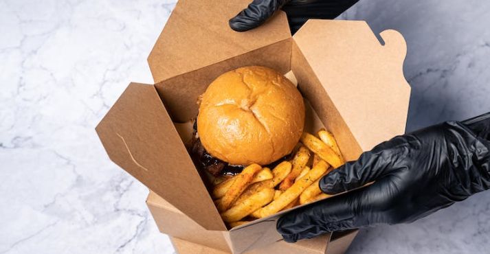 person packaging burger and fries in box
