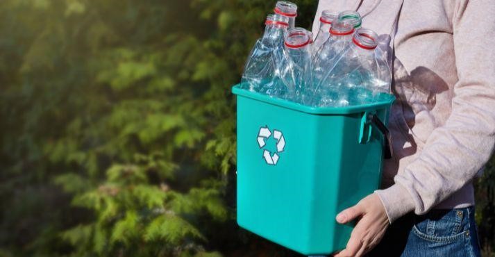 A-man-carrying-plastic-bottles-for-recycling-in-a-green-recycle-bin